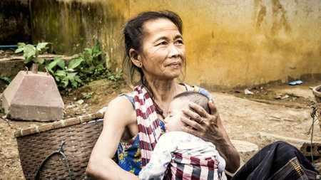 Laos - December 2015: Laos woman at a local bazaar with her babyのeditorial素材