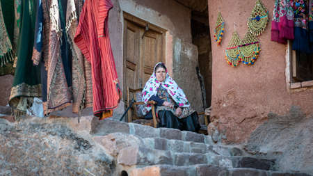 Abyaneh, Iran - May 2019: Iranian woman with traditional Abyaneh Persian dess sitting infront of her...