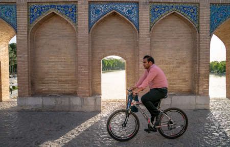 Isfahan, Iran - May 2019: Iranian man on a bicycle on Khaju bridge, built over Zayandeh river