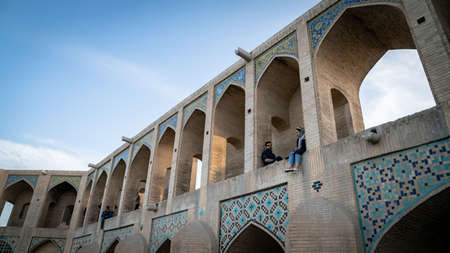 Isfahan, Iran - May 2019: Young Iranian couple sitting on Khaju bridge, built over Zayandeh river
