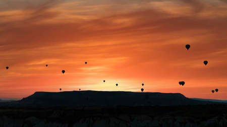 Cappadocia, Turkey - Silhouettes of hot air balloons flying in Cappadocia landscape with dramatic...