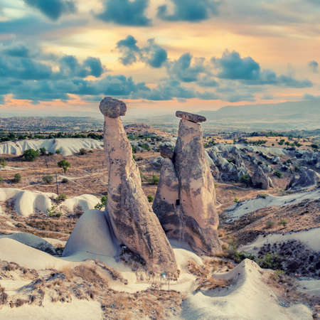 Fairy chimney rock formations of Cappadocia landscape under dramatic clouds. A hoodoo, also called a fairy chimney is a tall, thin spire of rock that protrudes from the bottom of a badlandの写真素材