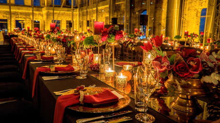 Istanbul, Turkey - February 2017: Luxury elegant table set with glasses covered in gold, lighted candles and red flowers in a historic building. Depth of field done intentionally.のeditorial素材