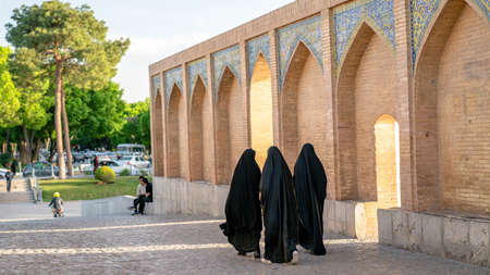 Isfahan, Iran - May 2019: Khaju bridge over Zayandeh river with tourists and local people walking...