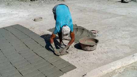Fes, Morocco - 10 September 2022: Moroccan craftsman making tiles with cement. He fills the mold...