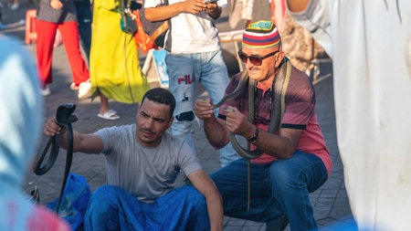 Marrakesh, Morocco - 15 September 2022: Snake charmer in Jemaa el Fnaa city square in the old city of Marrakesh. The square is full of many tourist activities.のeditorial素材