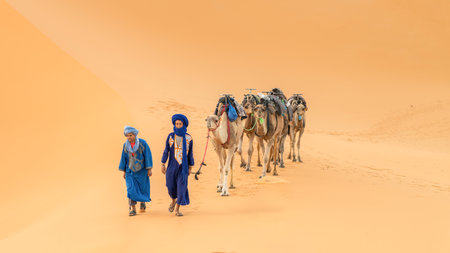 Sahara Desert, Morocco - 14 September 2022: Two Berber men leading a camel caravan across sand dunesのeditorial素材