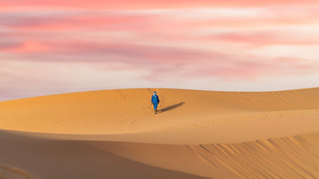 Unidentified Berber man in his traditional clothing, a long robe on sand dunes in Sahara Desert, Moroccoの写真素材