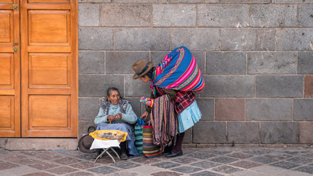 Cusco, Peru - 24 October 2023: Peruvian women selling souvenirs and food for the tourists sitting in...