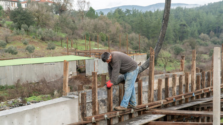 Istanbul, Turkey - 2 January 2024: Worker pouring wet cement mix from a concrete truck chute into a wall moldのeditorial素材