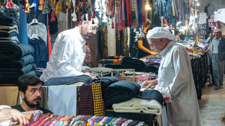 Gaziantep, Turkey - 14.10.2022: Man in traditional clothes buying clothing from the seller in historical Bedesten bazaarのeditorial素材