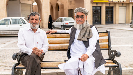 Yazd, Iran - 1 May 2019: Portrait of two Iranian men sitting at a bench in city parkのeditorial素材