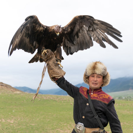 Issyk Kul, Kyrgyzstan - 23 May 2022: Eagle trainer with his golden eagle, showcasing traditional...