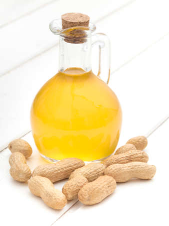 Peanut oil in a bottle on white wooden backgroundの写真素材