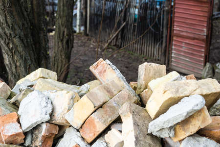 A pile of old used bricks with scratches and cracks from the old wall near the plot.