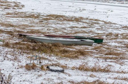 Moored wooden fishing boat on the bank of the Danube tributary in frozen water.の写真素材