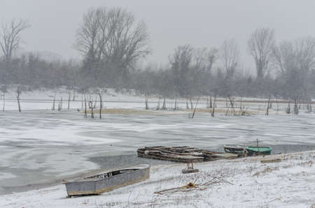 Moored wooden fishing boat on the bank of the Danube tributary in frozen water.の写真素材