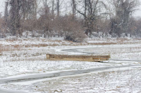 Moored wooden fishing boat on the bank of the Danube tributary in frozen water.の写真素材