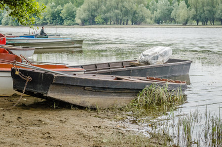 Wooden fishing boats tied to the shore. A view of small wooden fishing boats, moored to the shore of the lake in autumn.の写真素材