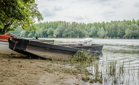 Wooden fishing boats tied to the shore. A view of small wooden fishing boats, moored to the shore of the lake in autumn.の写真素材