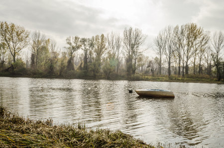 Wooden boat moored along the shore of the lake in water.
