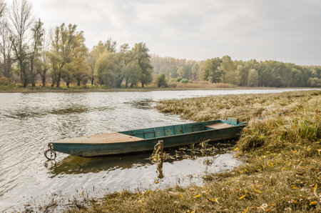 Wooden boat moored along the shore of the lake in water.