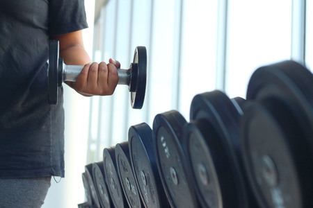 strong women hand takes a heavy dumbbell in gymの写真素材