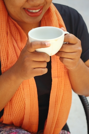 Woman wearing a black shirt is drinking coffee.の写真素材