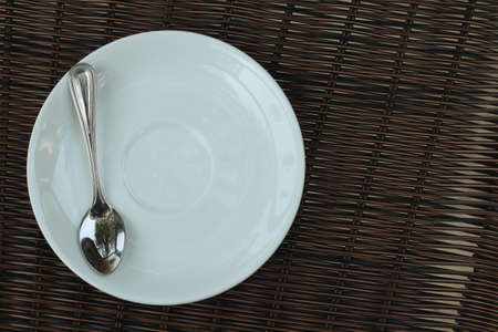 White dish with a spoon on a brown background.の写真素材