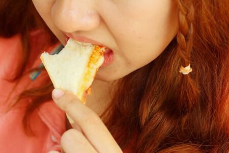 Woman eating a sandwich with ham and cheese.の写真素材