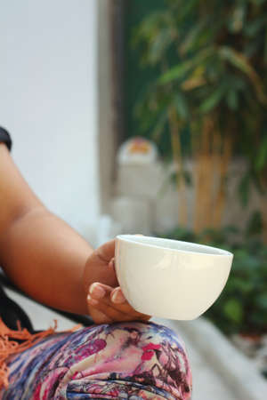 Woman wearing a black shirt is drinking coffee.の写真素材