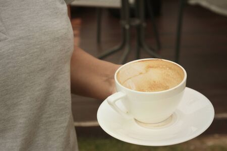 Woman holding a cup of coffee at the cafeの写真素材