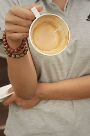 Woman holding a cup of coffee at the cafeの写真素材
