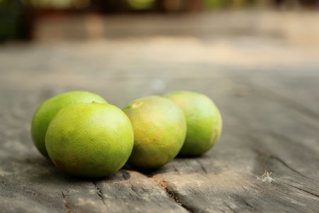 Green lemons on a background of woodの写真素材