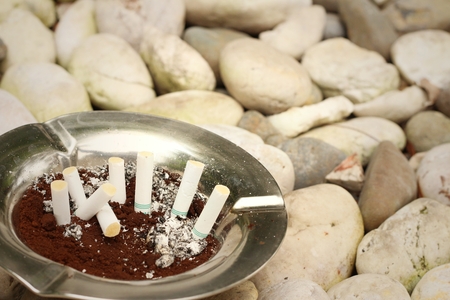 Cigarette with ashtray on a stone background