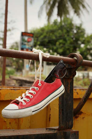 Red shoes with sunglasses hanging on steel.の写真素材