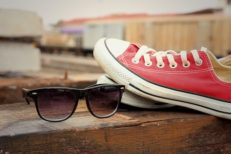 Red shoes with sunglasses on brown wood background.の写真素材