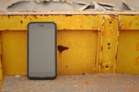 Smart phone on background of yellow steel.の写真素材