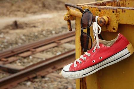 Red shoes with sunglasses hanging on steel.の写真素材