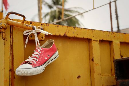 Red shoes hanging on a yellow steel.の写真素材