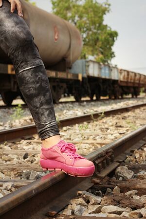 Woman wearing pink shoes at train station.の写真素材
