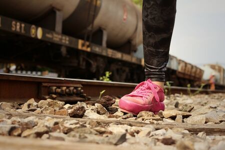 Woman wearing pink shoes at train station.の写真素材