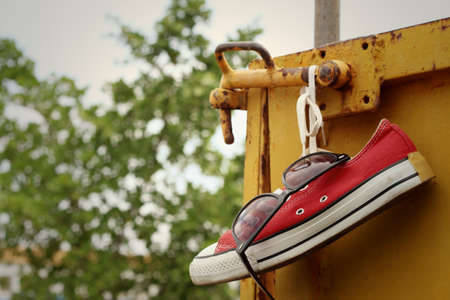 Red shoes with sunglasses hanging on steel.の写真素材