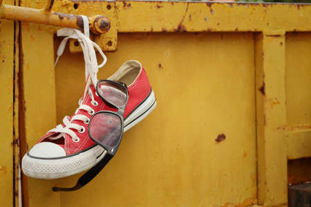 Red shoes with sunglasses hanging on steel.の写真素材