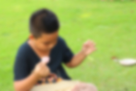 Blurred image of the boy eating macaron at the park.の写真素材