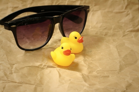 Sunglasses with yellow rubber duck on brown background.の写真素材