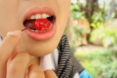 woman eating red cherry at cake shop.の写真素材