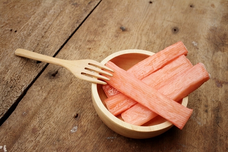 Crab stick in bowl on brown backgroundの写真素材