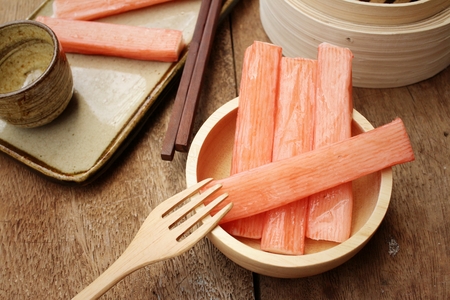 Crab stick in bowl on brown backgroundの写真素材