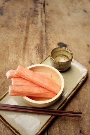 Crab stick in plate on brown backgroundの写真素材